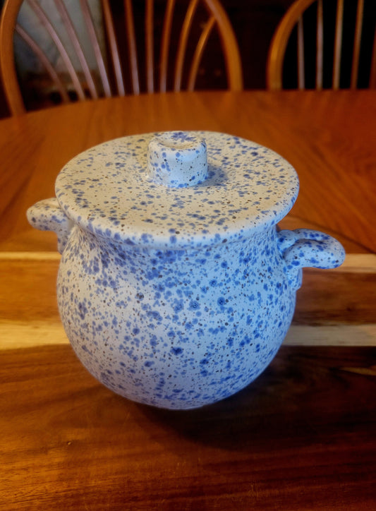 Blue speckled ceramic pot with lid on a wooden table