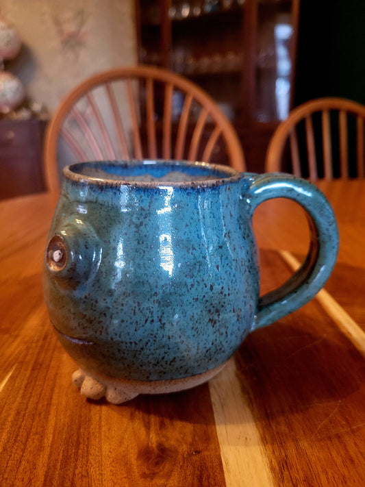 Blue ceramic mug shaped like a frog on a wooden table