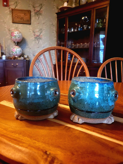 Two blue ceramic mugs with a textured surface on a wooden table.