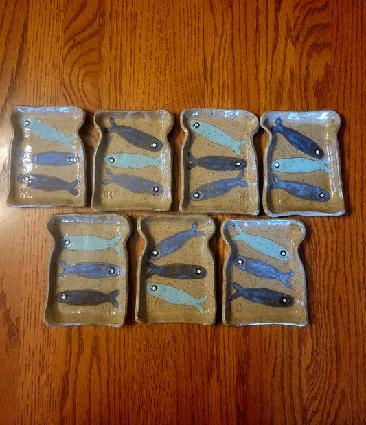 Set of ceramic plates with fish designs on a wooden surface
