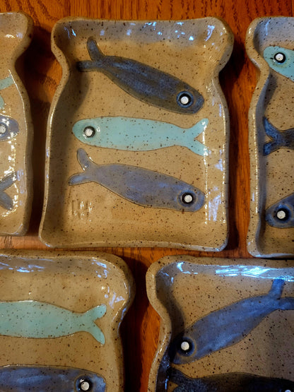Set of ceramic plates with fish designs on a wooden surface