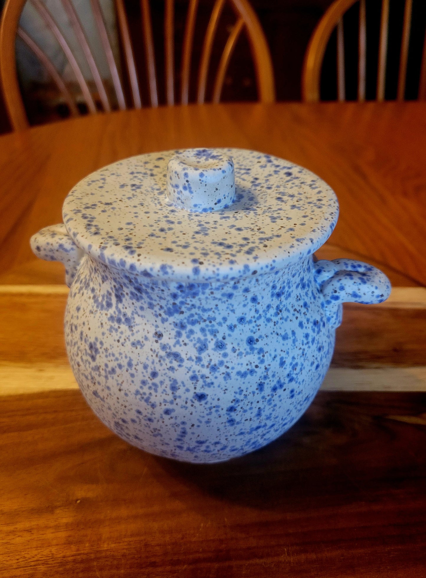 Blue speckled ceramic pot with lid on a wooden table