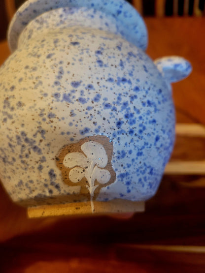 Speckled blue and white ceramic jar with a decorative label on a wooden surface