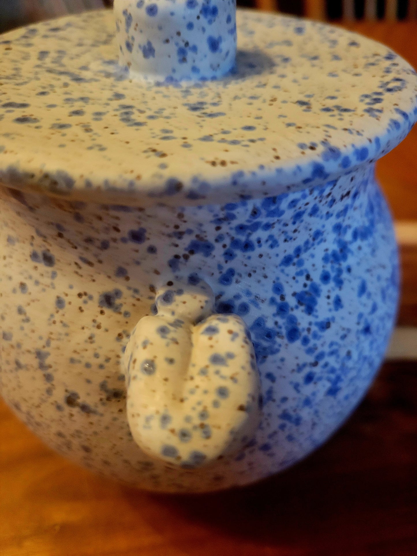 Speckled ceramic container with lid on a wooden surface