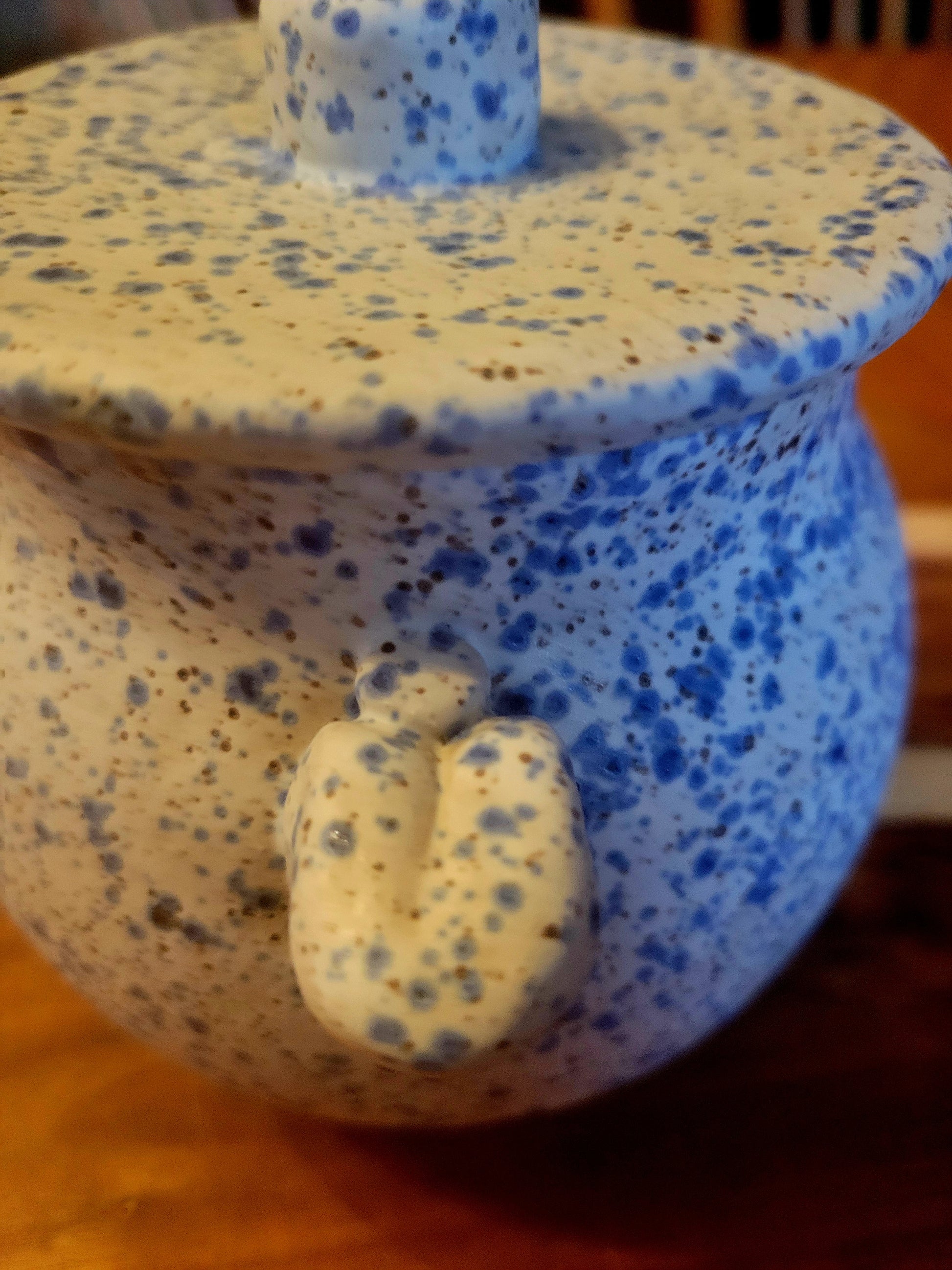 Speckled ceramic container with lid on a wooden surface