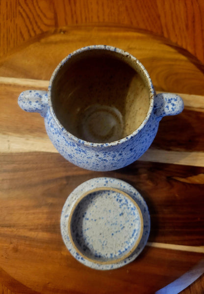 Speckled blue ceramic pot with lid on a wooden surface