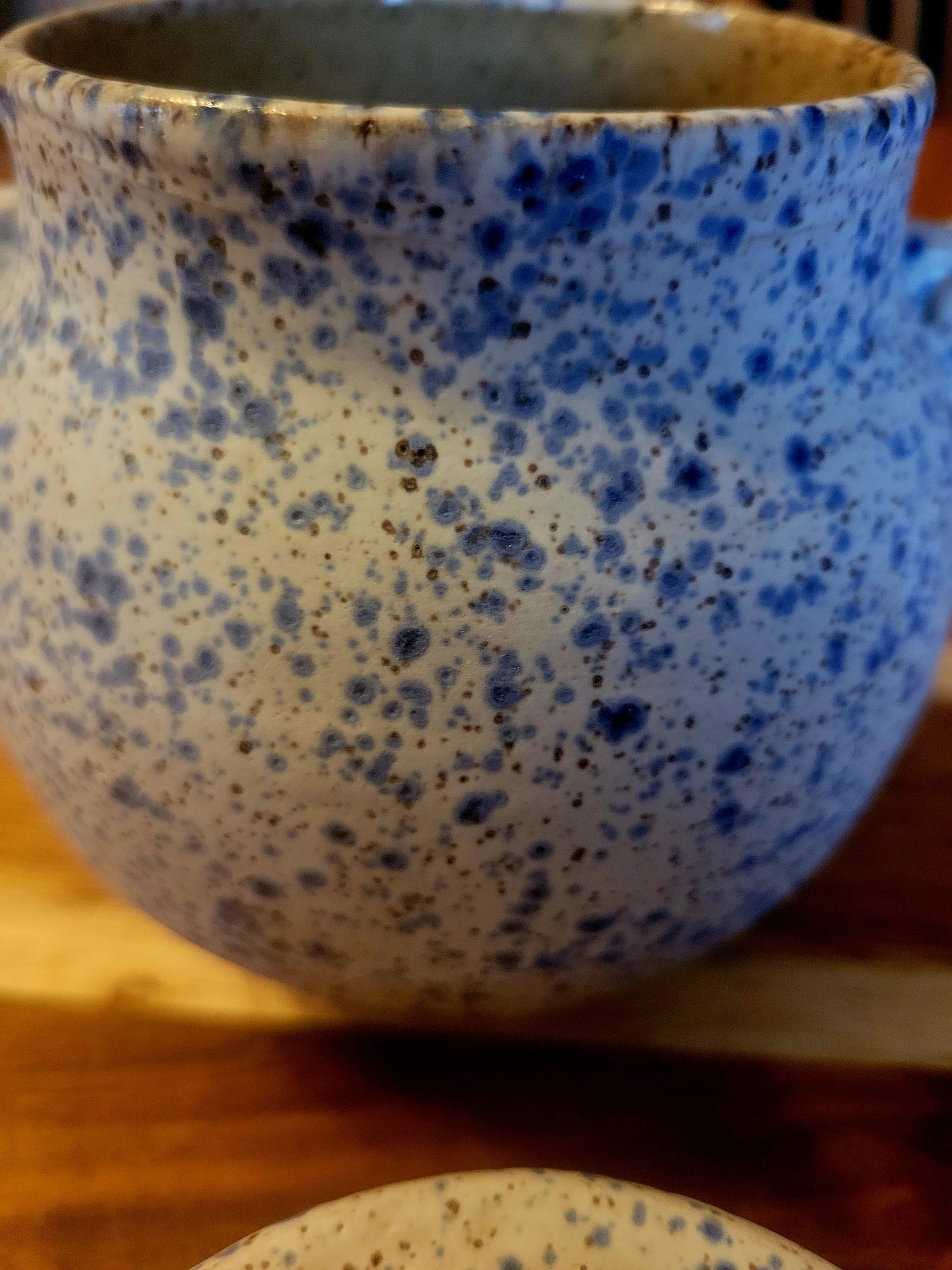 Speckled blue and beige ceramic ja on a wooden surface