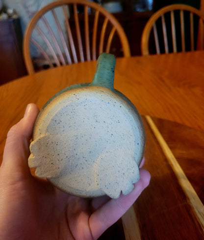 Hand holding a ceramic mug with a speckled design on a wooden table.