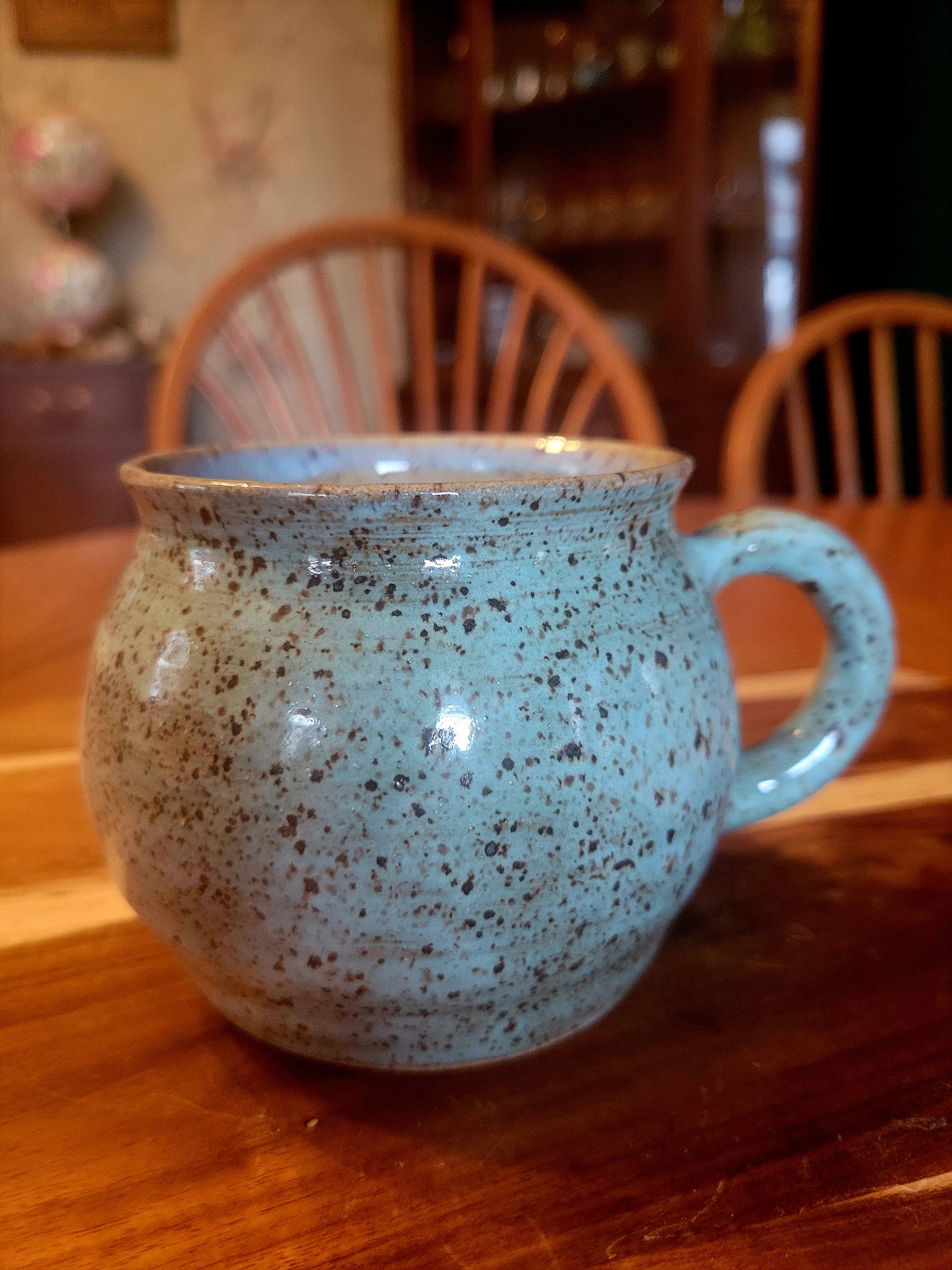 Speckled blue mug on a wooden table with blurred background