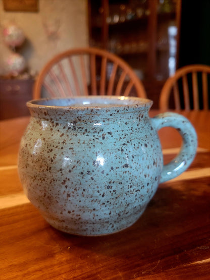 Speckled blue mug on a wooden table with blurred background