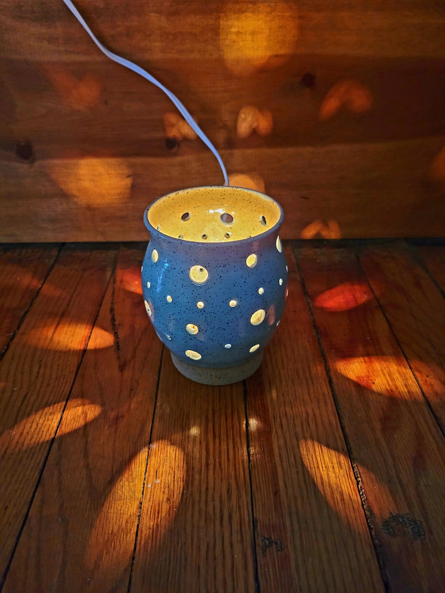 Blue ceramic lamp with white polka dots on a wooden floor