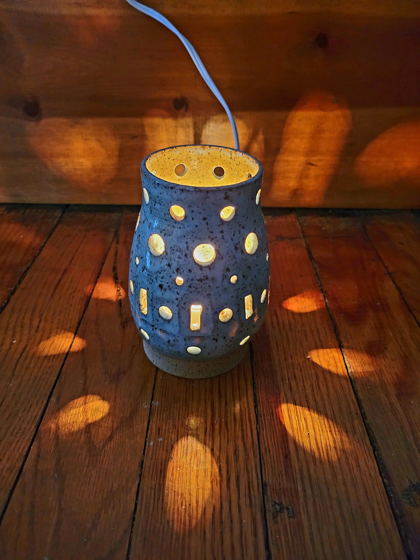 Blue ceramic lamp with white dots on a wooden surface