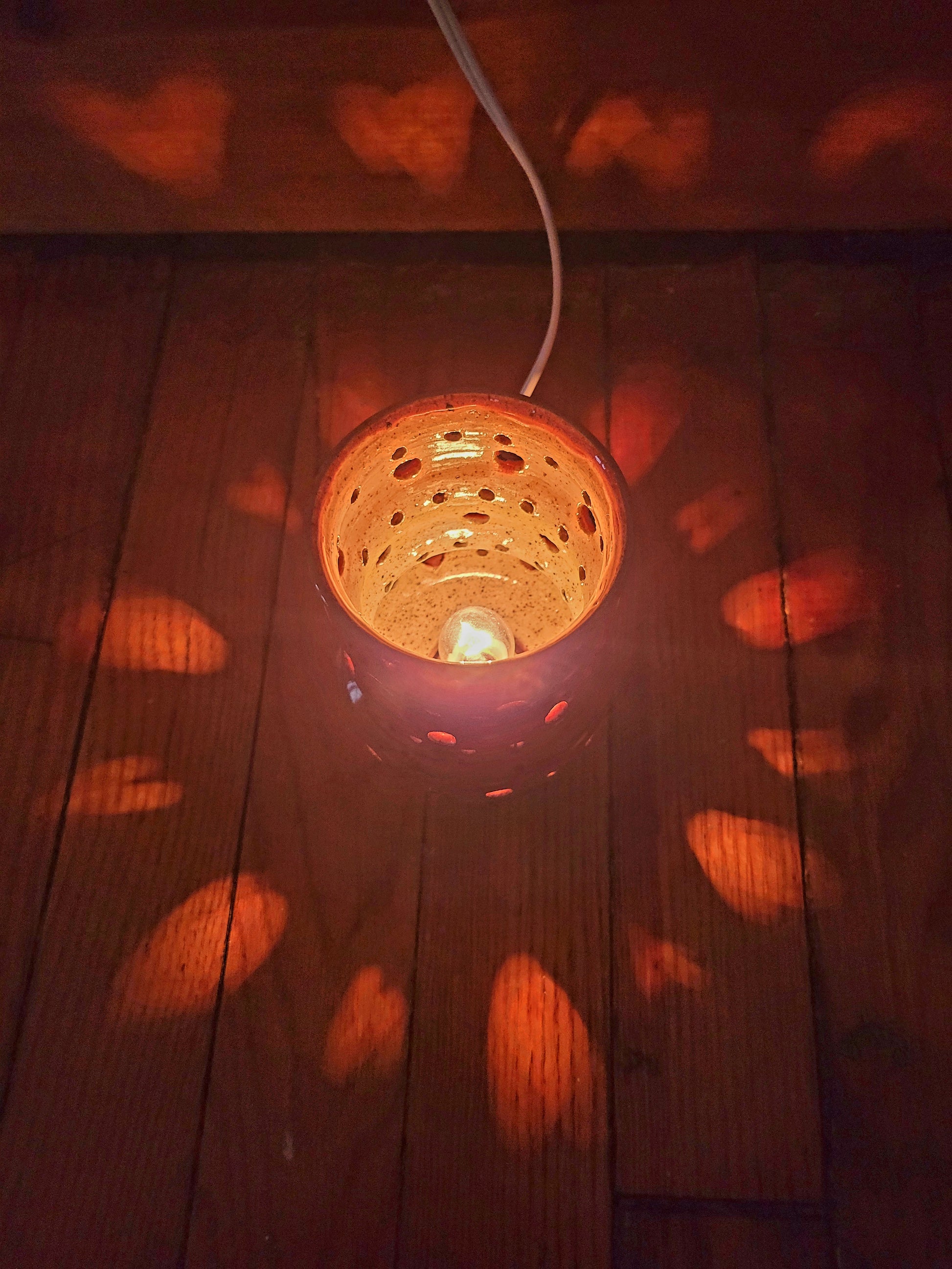 Decorative light fixture on a wooden surface with heart-shaped shadows