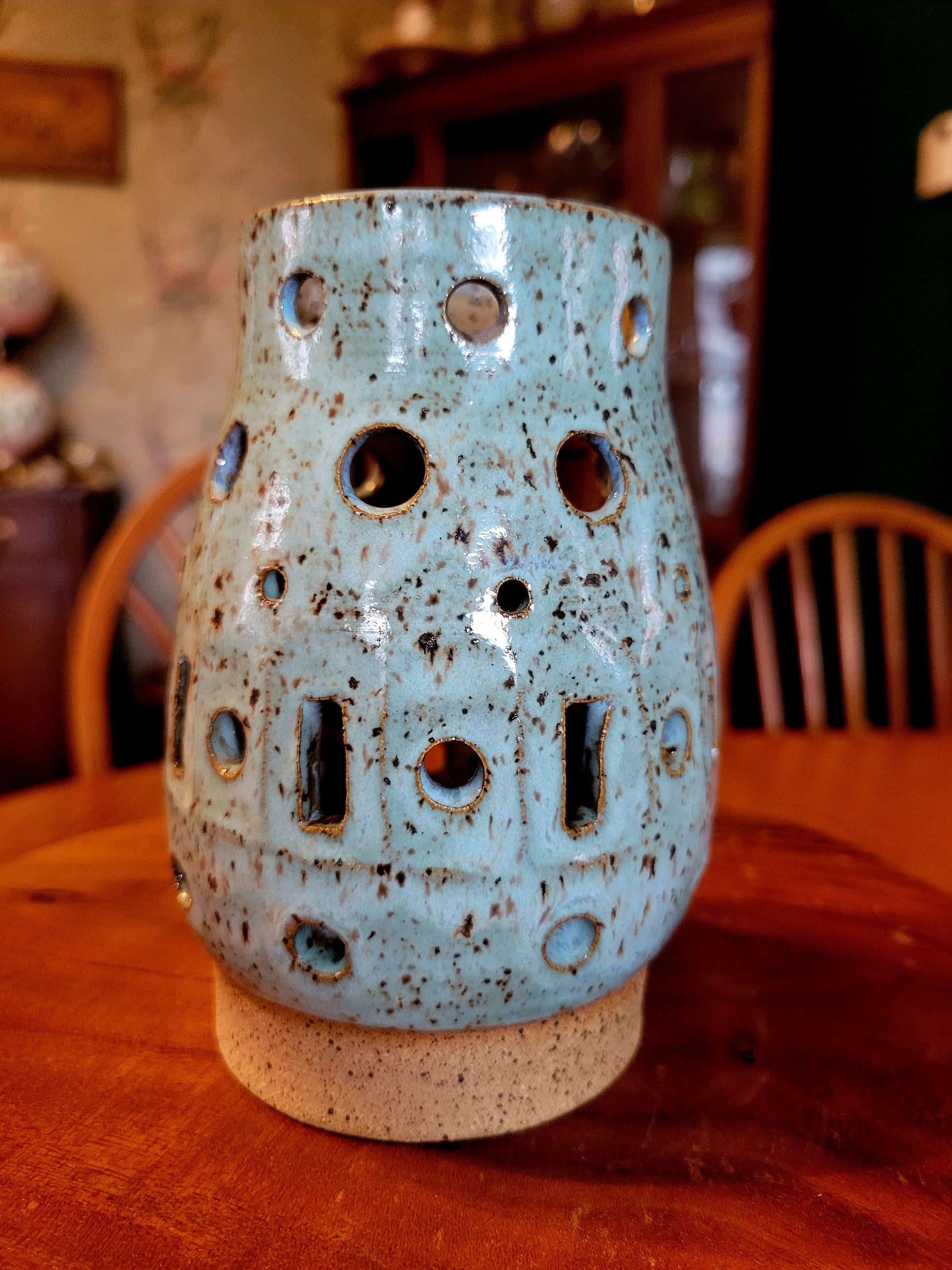 Blue ceramic lantern with holes on a wooden table