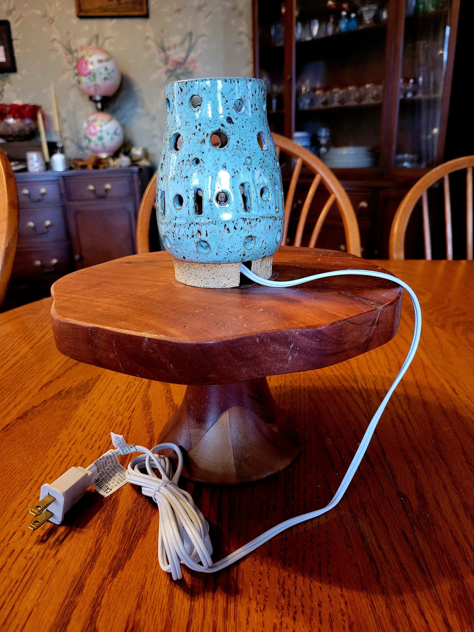 Blue ceramic lamp on a wooden base with a visible cord, set against a home interior background.