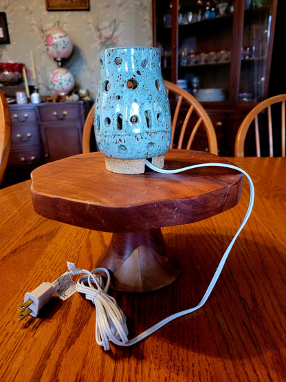 Blue ceramic lamp on a wooden base with a visible cord, set against a home interior background.