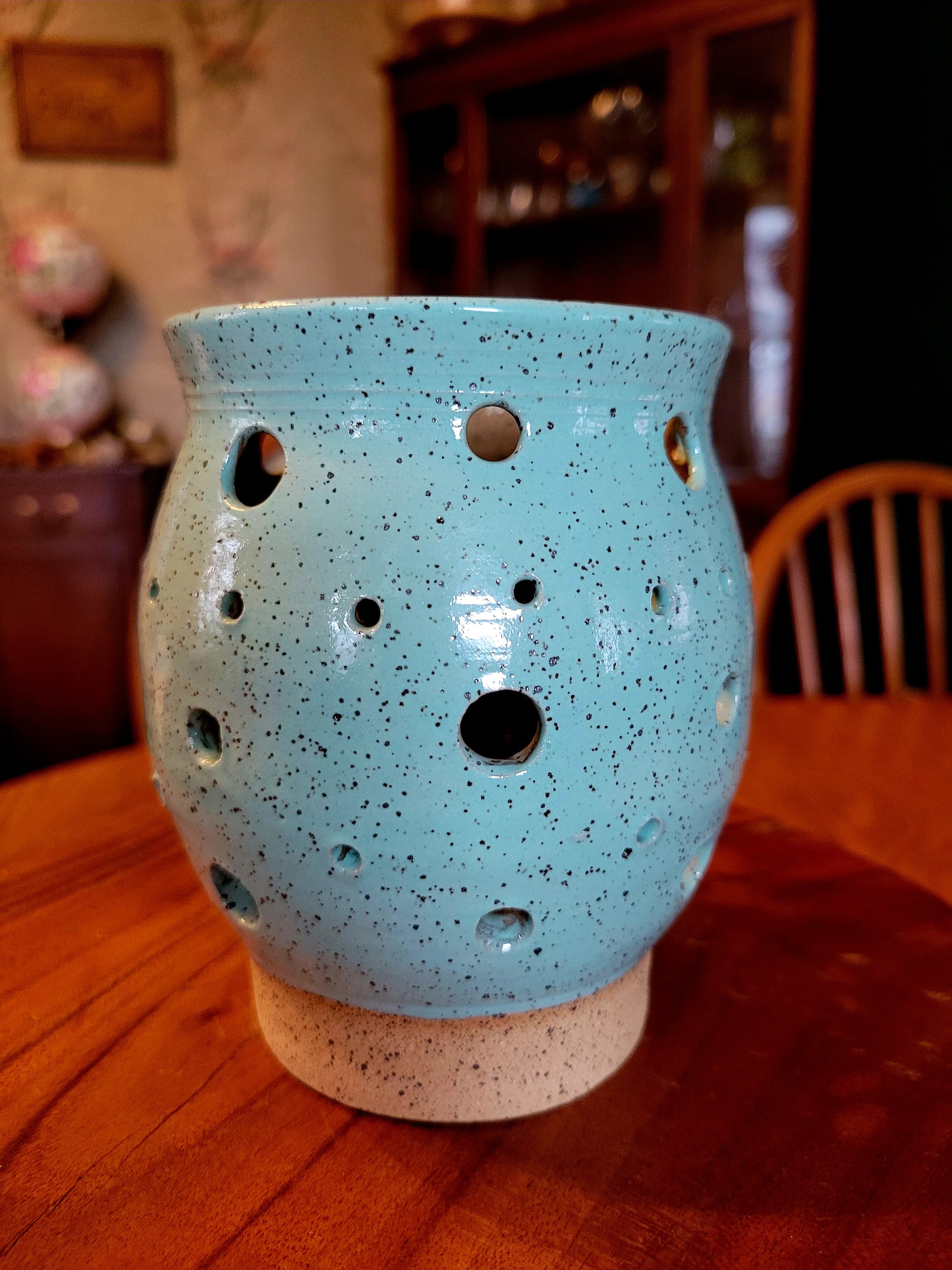 Blue ceramic lamp with holes on a wooden table