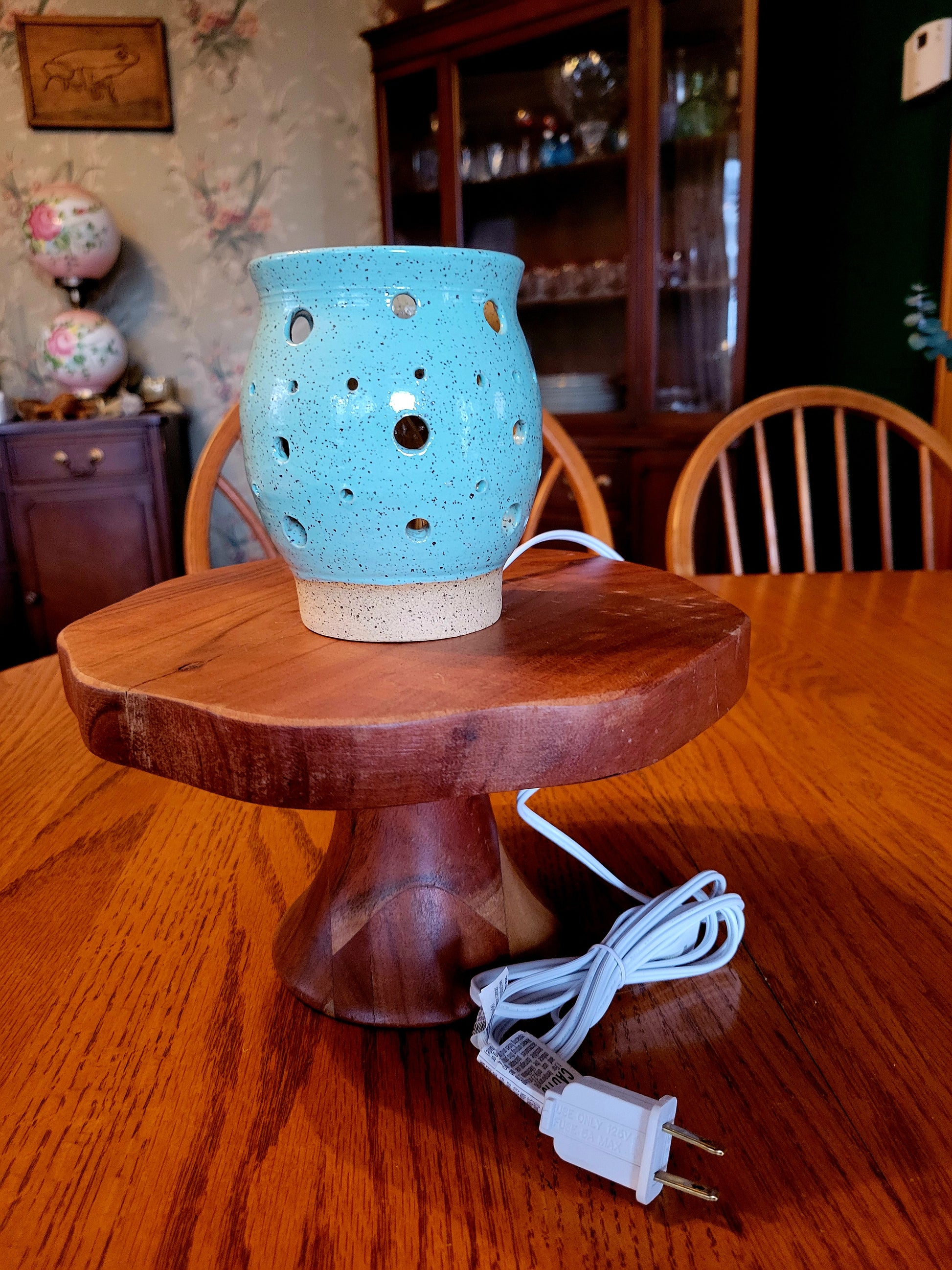 Blue ceramic lamp on a wooden stand with a chord in a room setting.